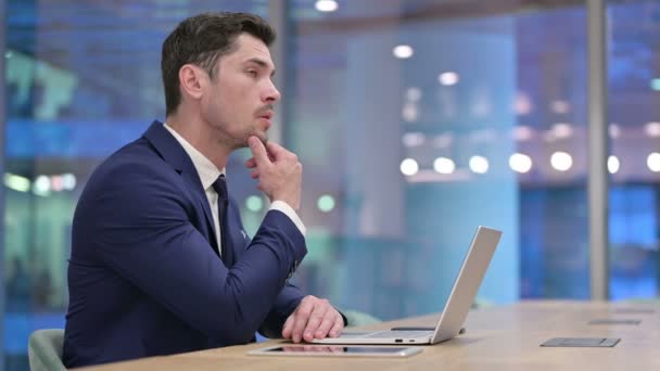 Empresário Pensando e trabalhando no laptop no escritório — Vídeo de Stock