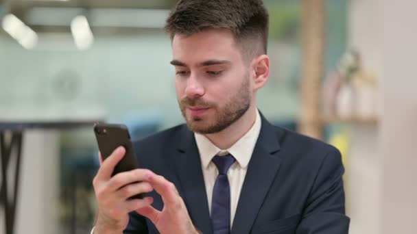 スマートフォンで成功を祝う興奮した若いビジネスマン — ストック動画