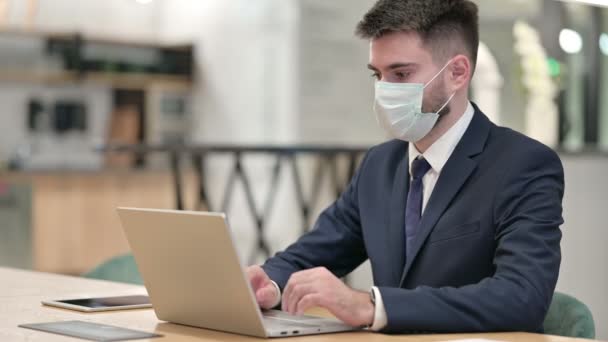 Mladý podnikatel s ochrannou maskou obličeje pracuje na notebooku — Stock video
