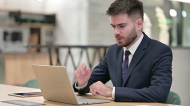Dizüstü bilgisayarı olan stresli genç iş adamı ofiste baş ağrısı çekiyor 