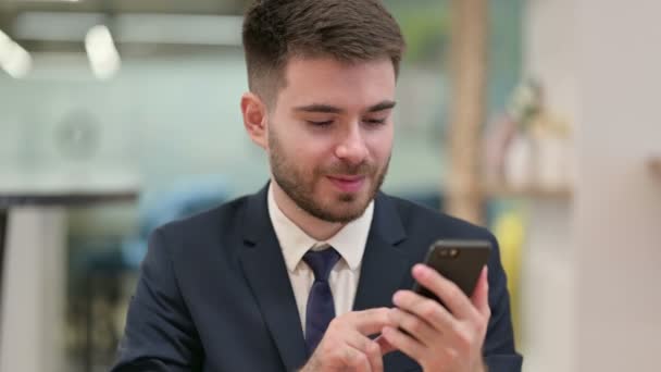 Młody biznesmen korzystający ze smartfona w pracy — Wideo stockowe