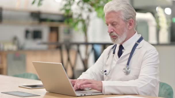 Senior oude arts werkt op Laptop in Office — Stockvideo
