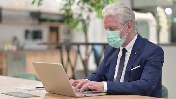 Senior gammal affärsman med ansiktsmask firar på laptop — Stockvideo