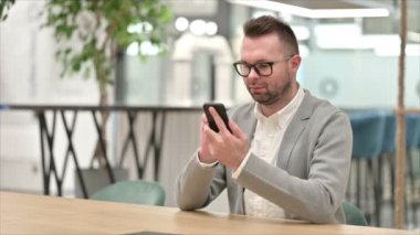 Ofiste akıllı telefon kullanan sıradan bir genç adam.