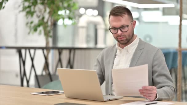 Nenucený mladý muž pracující na notebooku a dokumentech — Stock video