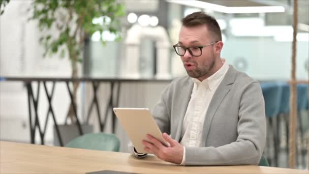 Nadšený ležérní mladý muž slaví úspěch na tabletu v kanceláři — Stock video