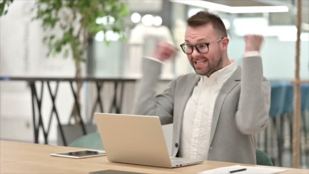 Nadšený ležérní mladý muž slaví úspěch na notebooku v kanceláři — Stock video