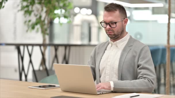 Unavený ležérní mladý muž s notebookem s bolestí v krku v kanceláři — Stock video