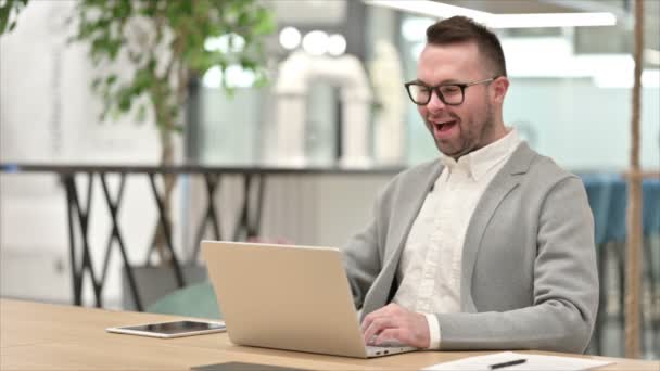 Nenucený mladý muž mluví na video chat na notebooku v kanceláři — Stock video