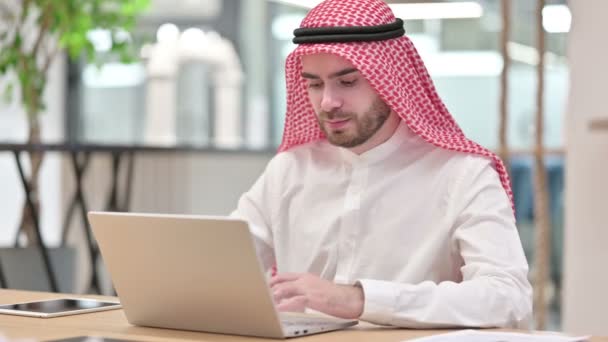 Empresario árabe sin expresión con computadora portátil mirando a la cámara — Vídeo de stock