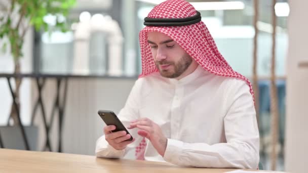 Atrakcyjny arabski biznesmen korzystający ze smartfona w biurze — Wideo stockowe