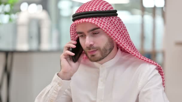 Веселый арабский бизнесмен разговаривает по смартфону в офисе — стоковое видео