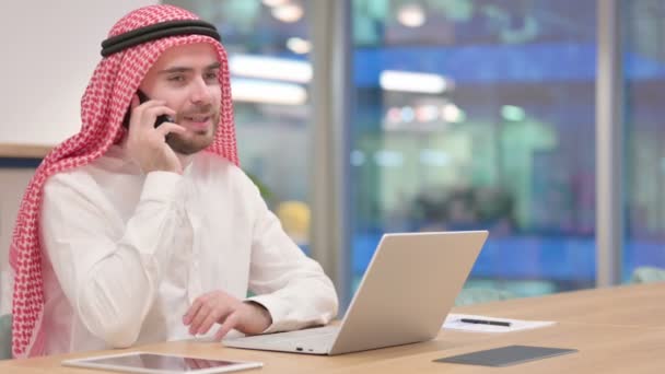 Arabische zakenman met laptop aan het praten op Smartphone in Office — Stockvideo