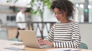 Dizüstü bilgisayarlı genç Afrikalı İş kadını Ofiste Kameraya Gülümsüyor