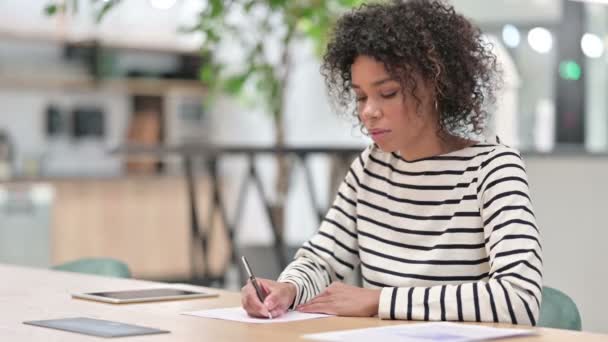 Сосредоточенные африканские предпринимательницы пишут на бумаге в офисе — стоковое видео