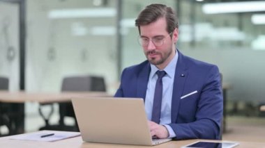 Dizüstü bilgisayarlı genç iş adamı Kameraya gülümsüyor 