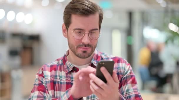 Portrét vzrušeného návrháře mužského pohlaví oslavující úspěch na chytrém telefonu — Stock video