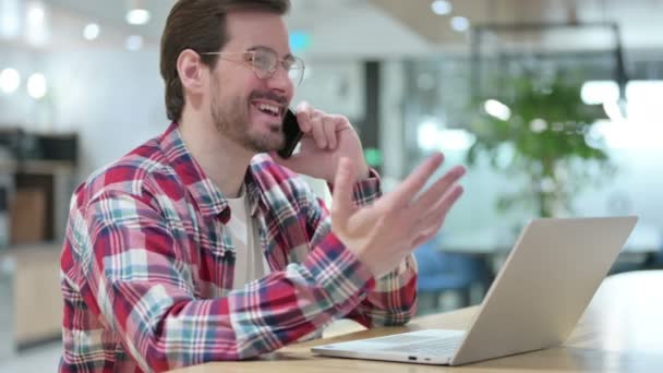 Designer Masculino trabalhador com Laptop Talking no Smartphone — Vídeo de Stock