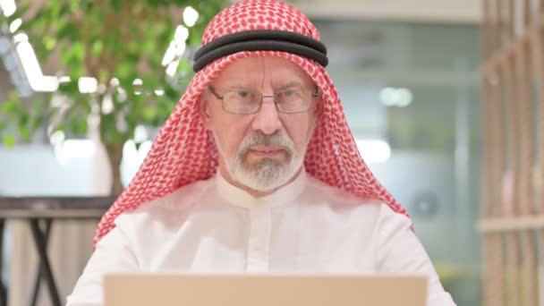 Alter arabischer Geschäftsmann mit Laptop blickt in die Kamera — Stockvideo