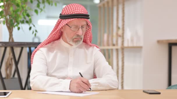 Старый арабский бизнесмен пишет на бумаге — стоковое видео