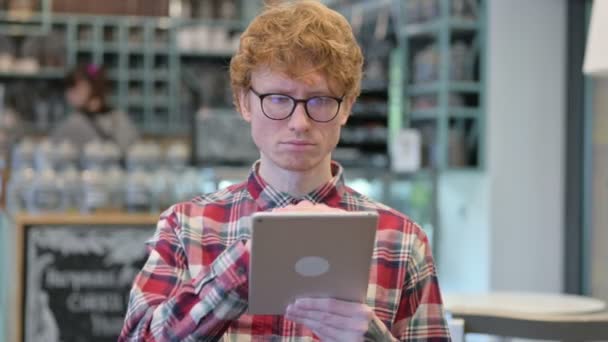 デジタルタブレットを使用して深刻な若い赤毛の男 — ストック動画