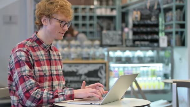 Jeune rousse homme avec ordinateur portable montrant pouces vers le bas — Video