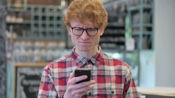 Mladý rusovlasý muž reaguje na selhání na chytrém telefonu — Stock video