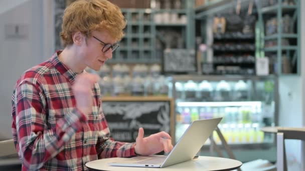 カフェでラップトップを使用して首の痛みを持つ若い赤毛の男 — ストック動画