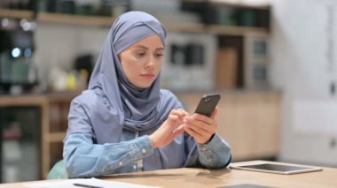 İş yerinde akıllı telefon kullanan çekici bir Arap kadını. 