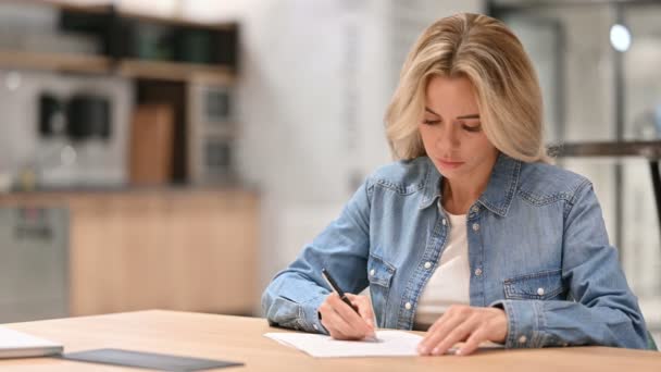Молодая случайная женщина, пишущая на бумаге на работе — стоковое видео