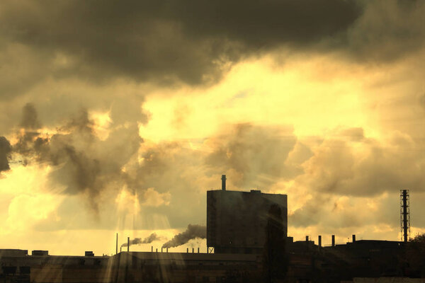 Industrial plant pollutes atmosphere and environment with harmful emissions from chemical processing through factory chimneys against cloudy sky