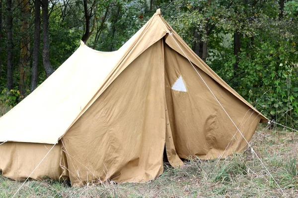 Old canvas tent in tourist camp in summer on background of green trees
