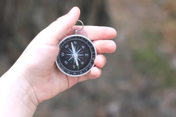 Old classic navigation compass in childs hand on natural background