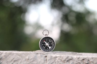 Pusula ile turizmin sembolü olarak doğal arka planda yuvarlak pusula, pusula ile seyahat ve pusula ile açık hava aktiviteleri