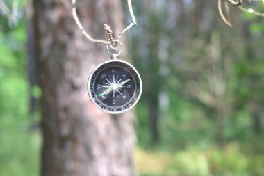 Pusula ile turizmin sembolü olarak doğal arka planda yuvarlak pusula, pusula ile seyahat ve pusula ile açık hava aktiviteleri