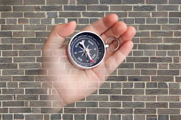 Abstract photo with compass in hand on brick wall background as symbol of tourism with compass, travel with compass and outdoor activities with compass