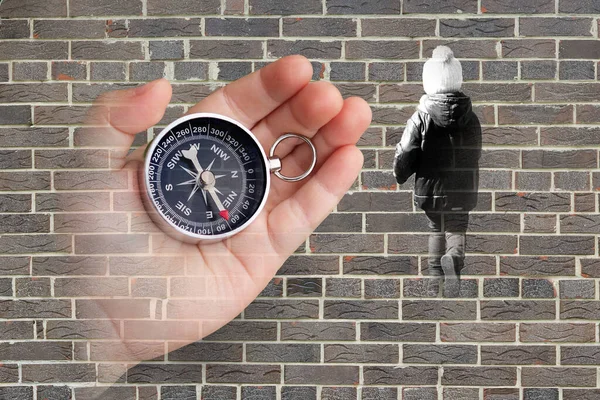 Abstract photo with compass in hand and with running child on brick wall background as symbol of tourism with compass, travel with compass and outdoor activities with compass