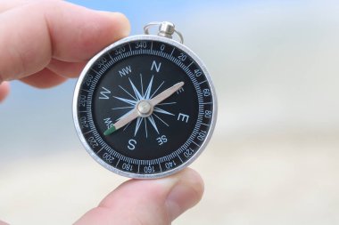 Pusula ile turizmin sembolü olarak kumlu sahil ve mavi denizin arka planına karşı klasik pusula, pusula ile seyahat ve pusula ile açık hava aktiviteleri