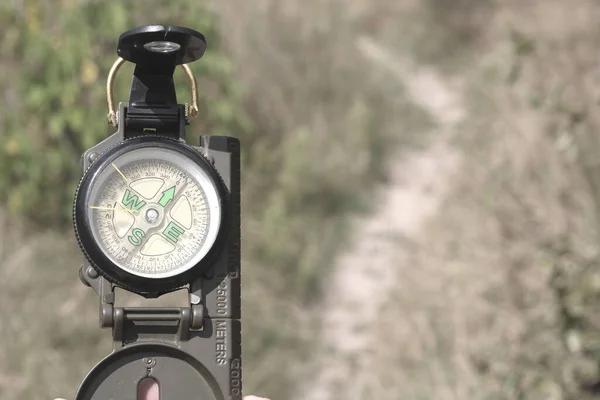 Old classic navigation compass on background of path as symbol of tourism with compass, travel with compass and outdoor activities with compass