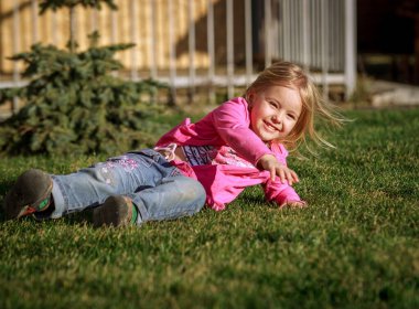 Güzel çocuk sarışın kız yazın güneşte yeşil çimlerde yürür.