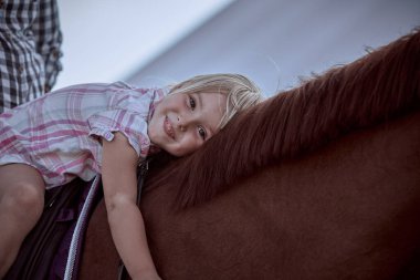 Büyük kırmızı bir atı olan güzel sarışın kız.