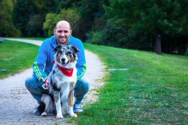 Genç adam diz yanında Avustralya çoban köpeği