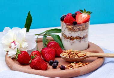 Yoğurtlu granola, mavi arka planda çilek ve frenk üzümü.