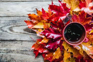 ahşap arka plan üzerinde çay kupa ile kırmızı sarı sonbahar yaprakları