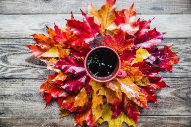 ahşap arka plan üzerinde çay kupa ile kırmızı sarı sonbahar yaprakları