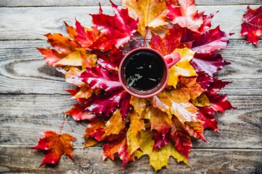 ahşap arka plan üzerinde çay kupa ile kırmızı sarı sonbahar yaprakları