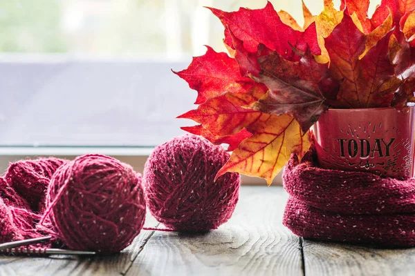 autumn leaves in a mug with tangles of yarn