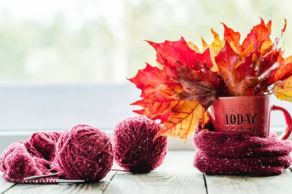 autumn leaves in a mug with tangles of yarn