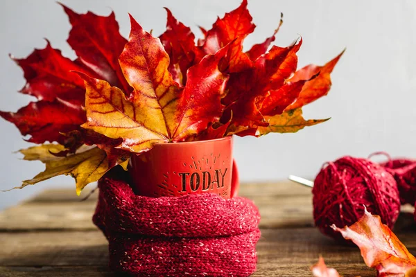 autumn leaves in a mug with tangles of yarn