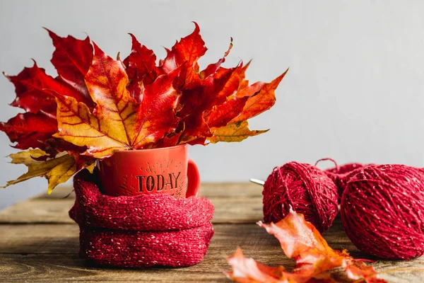 autumn leaves in a mug with tangles of yarn